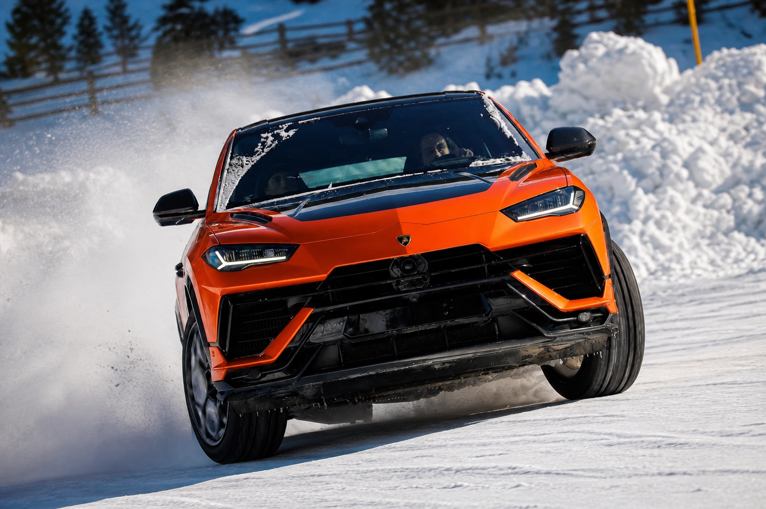 Orange Lamborghini Urus driving on a snowy route